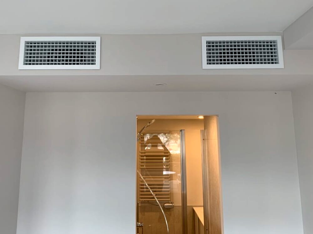 Deux grilles de soufflage encastrées en retombée de plafond dans une pièce finie