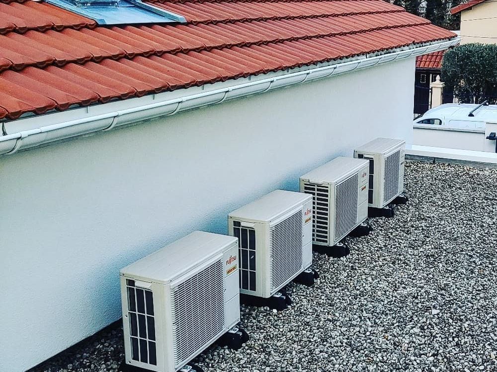 Plusieurs groupes extérieurs de climatisation alignés et calés le long d'une façade